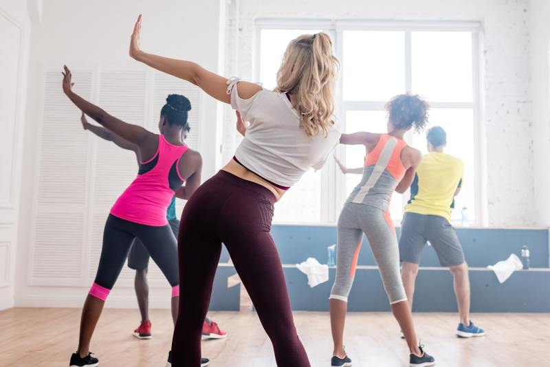 Back view of multiethnic zumba dancers performing movements in dance studio